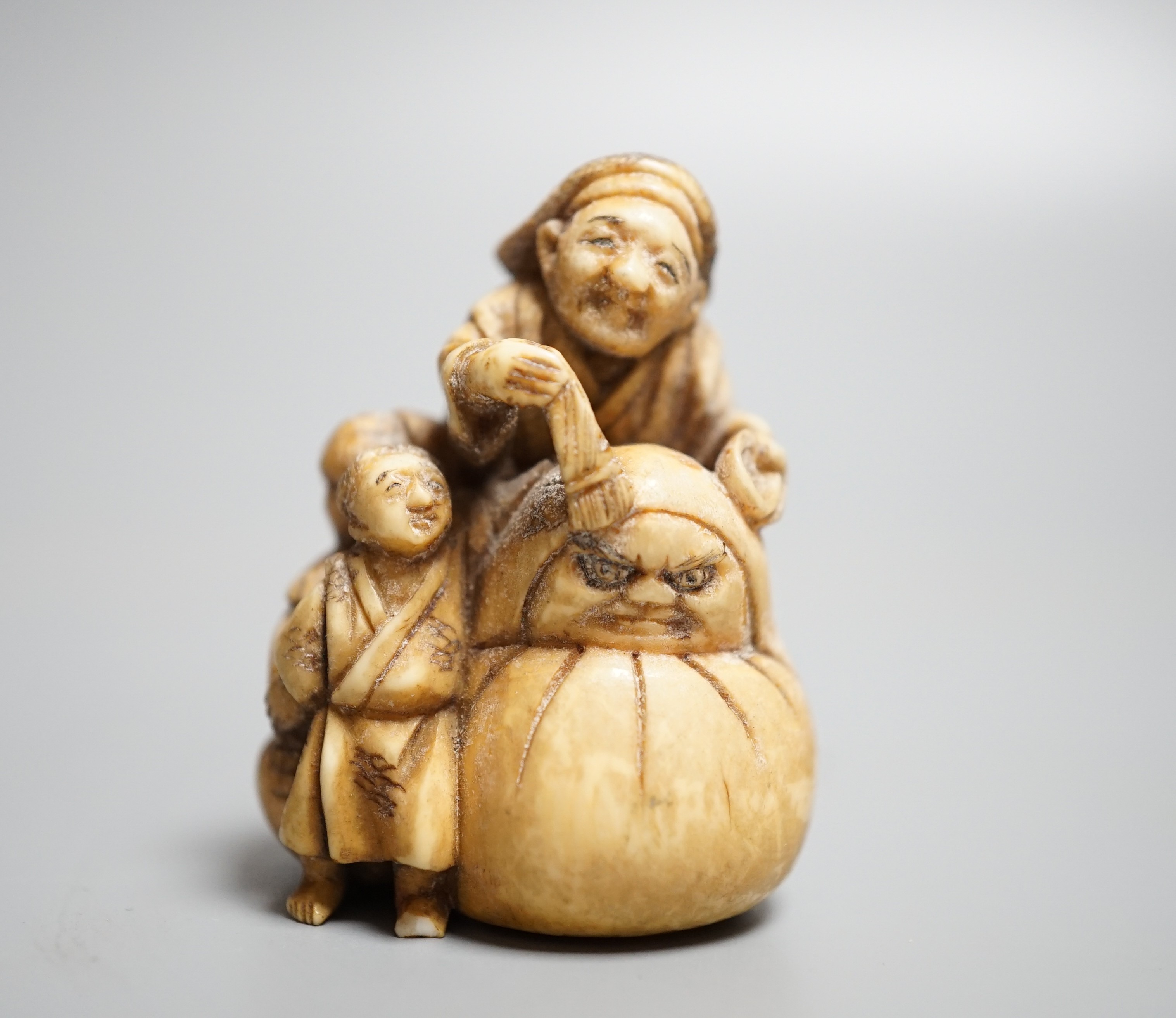 A Japanese ivory netsuke of an artisan and apprentice painting a Daruma doll, early 20th century,height 4cm